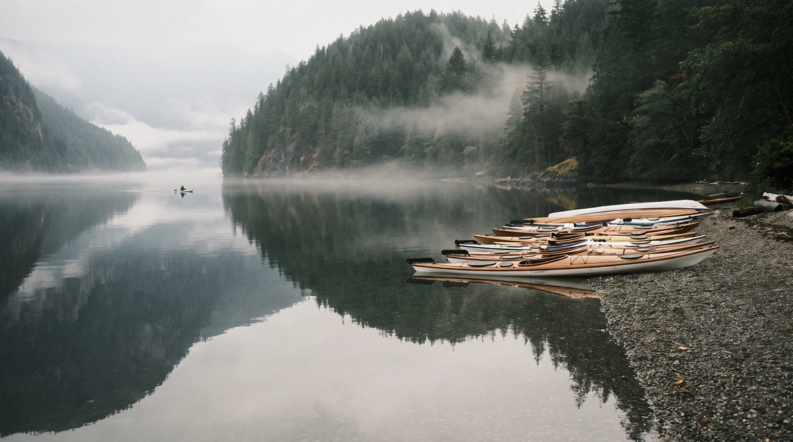 Kayaks on the calm water of Deep Cove at the head of Indian Arm, North Vancouver, with forested slopes rising on both sides of the fjord