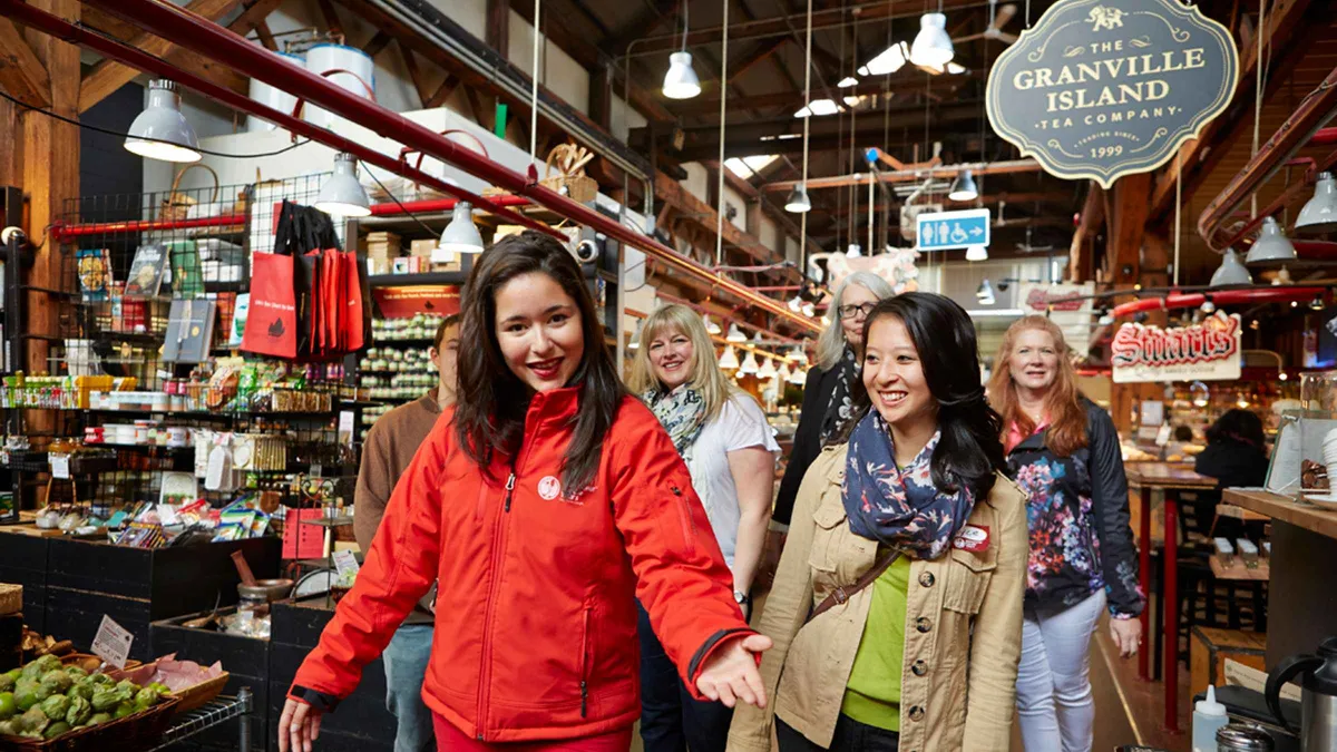 Guide introducing a cheese vendor inside Granville Island Public Market, Granville Island market tour with tastings Vancouver