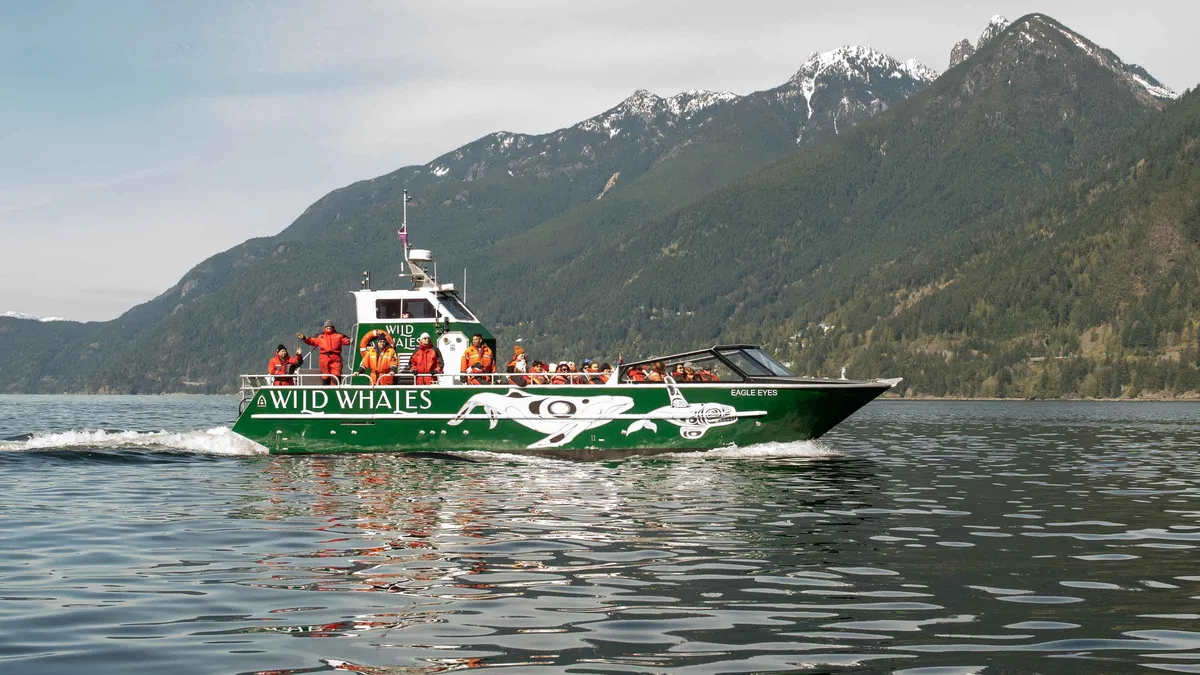 Passengers on the open deck of a catamaran watching orcas in the Salish Sea, open-air whale watching tour from Granville Island Vancouver