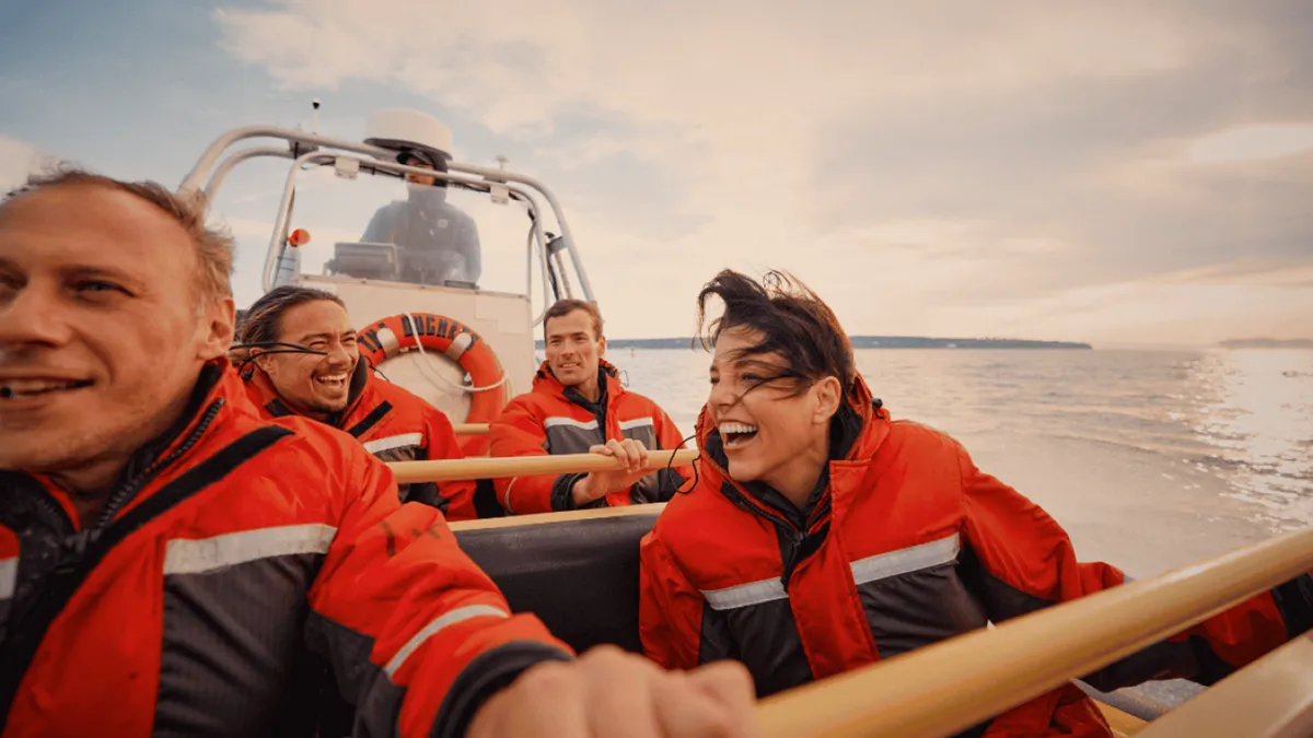 Red-suited passengers in a fast zodiac speeding past the Vancouver skyline, waterfront sightseeing tour of the city and harbour